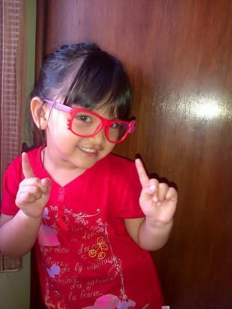 Mira wearing red glasses as a child